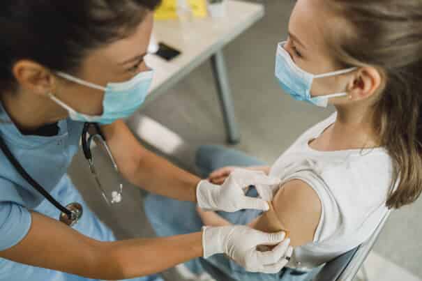 girl receiving a bandaid after a vaccine from a nurse