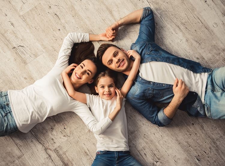 A couple and their daughter laying on the floor of a house
